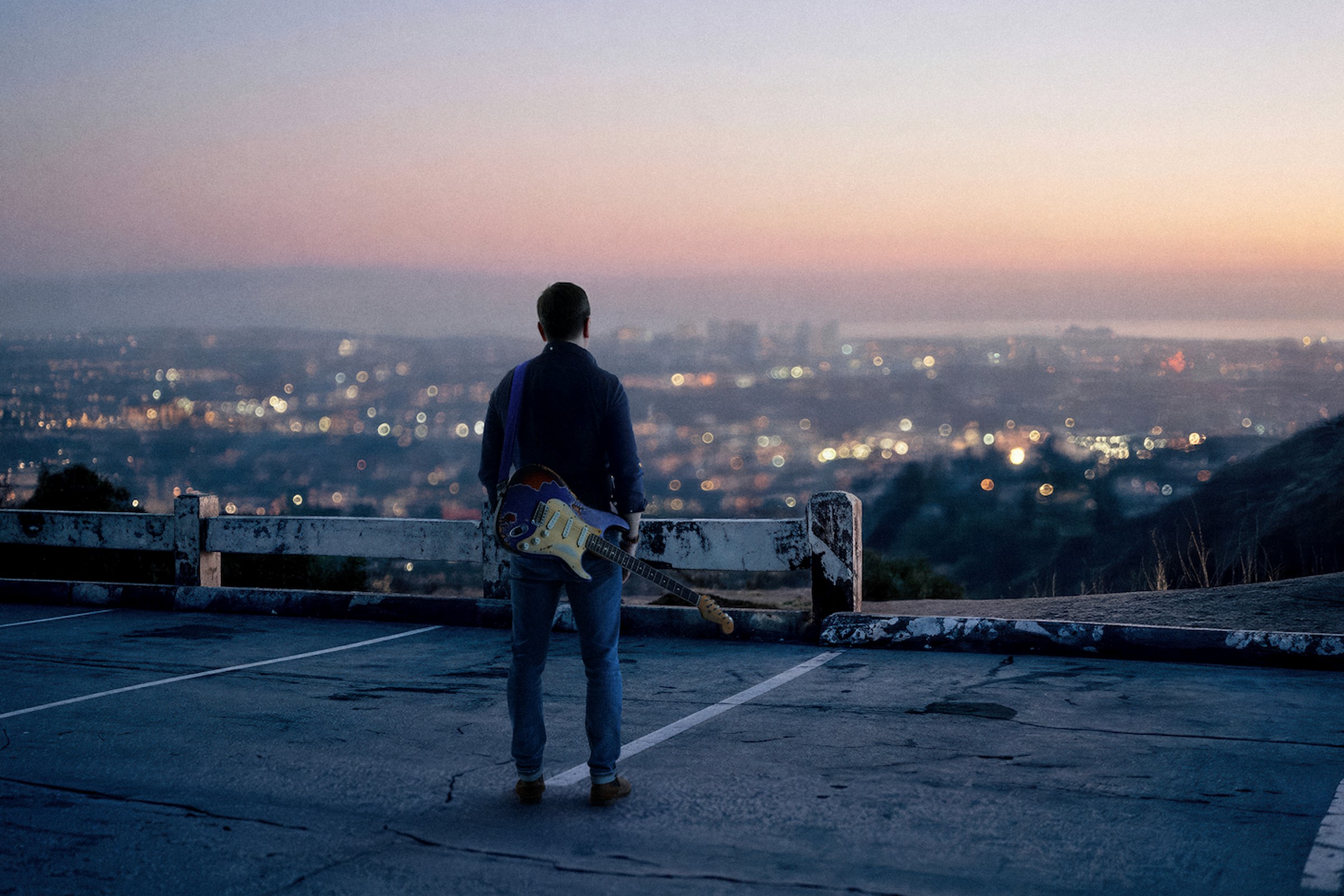 R.G. DeGuire overlooking a distant city with a guitar